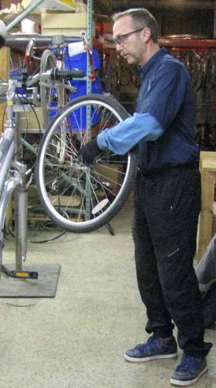 Don holding a bike wheel in the repair area.